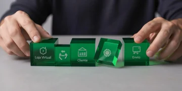 Mãos de uma pessoa ajustando blocos de acrílico verde representando o fluxo de dropshipping em uma mesa cinza, sob iluminação de estúdio difusa, com foco na estratégia do negócio online.